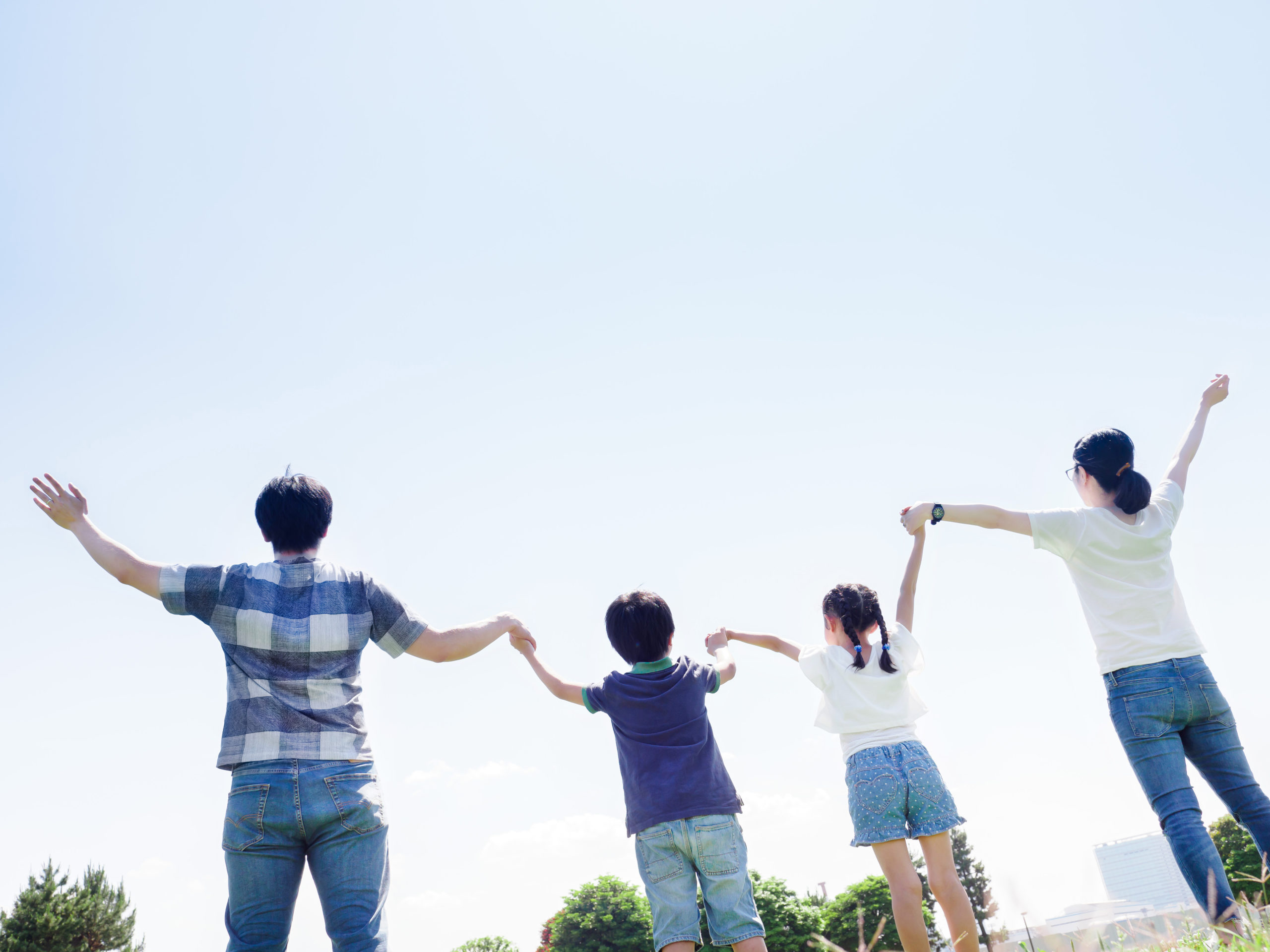 晴れた公園で手をつなぐ家族